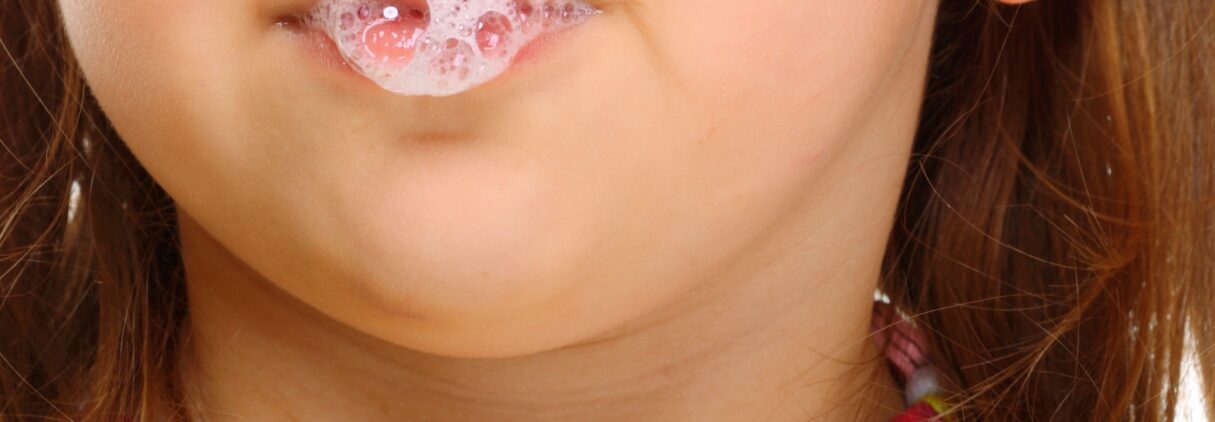 Close up little girl doing fun saliva bubbles