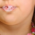 Close up little girl doing fun saliva bubbles