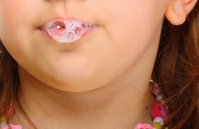 Close up little girl doing fun saliva bubbles